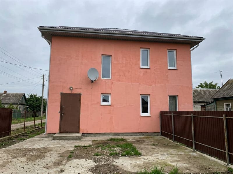 Дом с розовой штукатуркой и хаотично расположенными окнами
